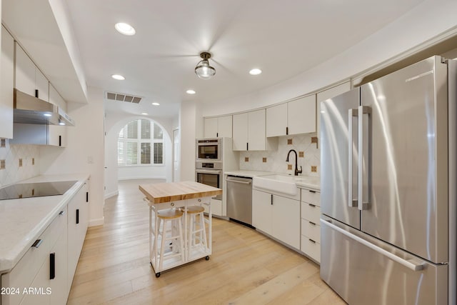 kitchen featuring a kitchen island, white cabinetry, sink, and appliances with stainless steel finishes