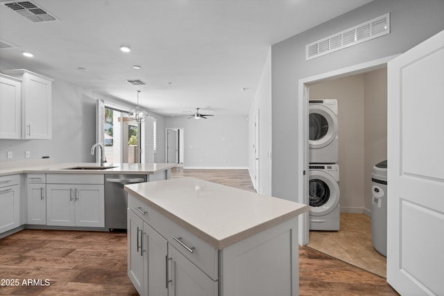 2511 W Queen Creek Rd Unit 116, Chandler, AZ 85248 - kitchen featuring dishwasher, stacked washing machine and dryer, a sink, a peninsula, and light countertops