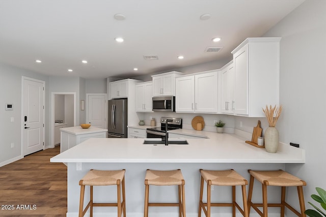 2511 W Queen Creek Rd Unit 116, Chandler, AZ 85248 - kitchen with appliances with stainless steel finishes, a peninsula, recessed lighting, a breakfast bar area, and white cabinets