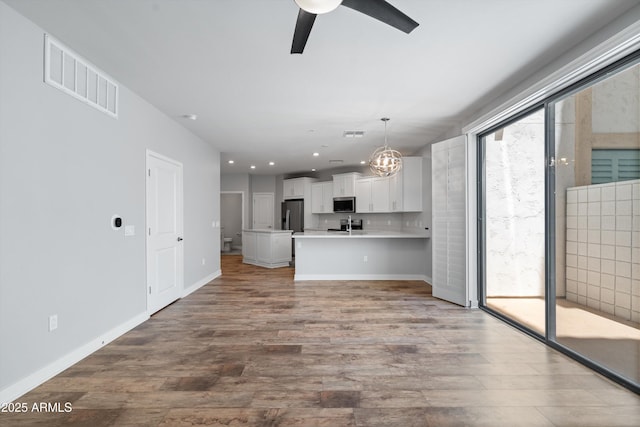 2511 W Queen Creek Rd Unit 116, Chandler, AZ 85248 - kitchen with appliances with stainless steel finishes, ceiling fan, wood finished floors, a chandelier, and white cabinets