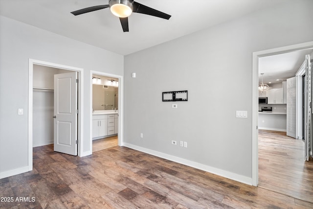 2511 W Queen Creek Rd Unit 116, Chandler, AZ 85248 - unfurnished bedroom with a walk in closet, wood finished floors, baseboards, ensuite bathroom, and a chandelier