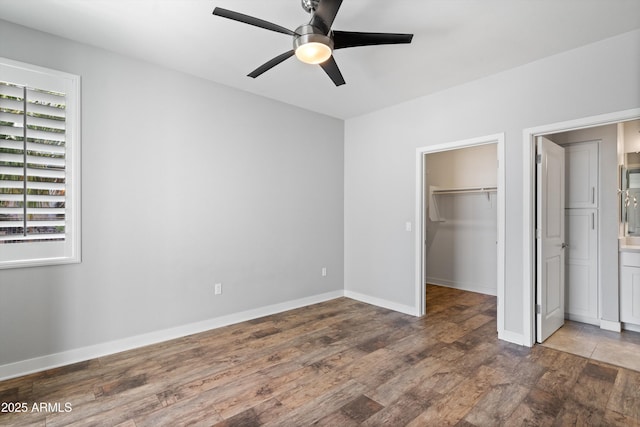2511 W Queen Creek Rd Unit 116, Chandler, AZ 85248 - unfurnished bedroom with wood finished floors, a spacious closet, a closet, baseboards, and a ceiling fan