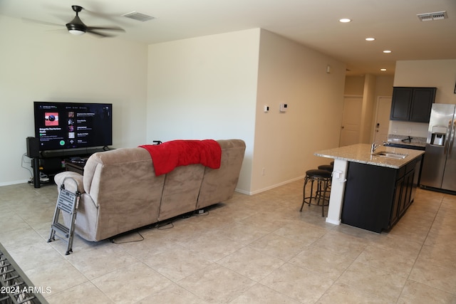 tiled living room with ceiling fan and sink