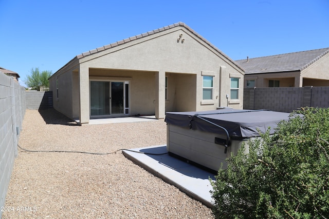 back of property with a hot tub and a patio area