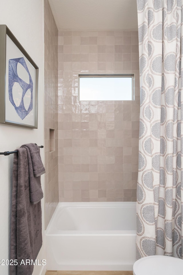 bathroom featuring shower / tub combo and toilet