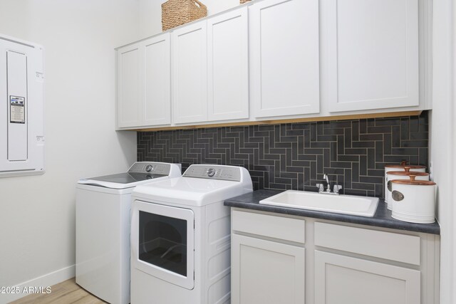 washroom with cabinets, electric panel, sink, light hardwood / wood-style flooring, and separate washer and dryer