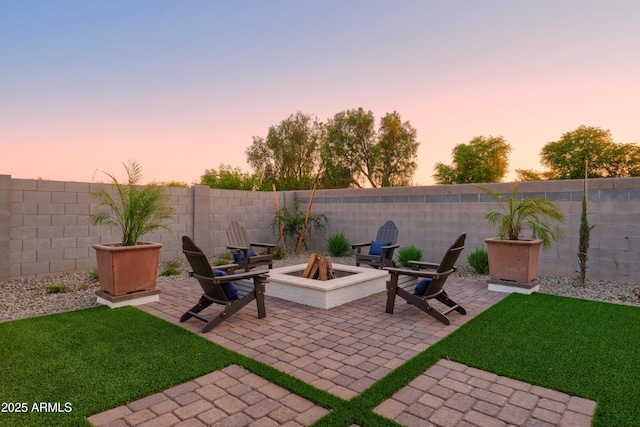 patio terrace at dusk with an outdoor fire pit and a lawn