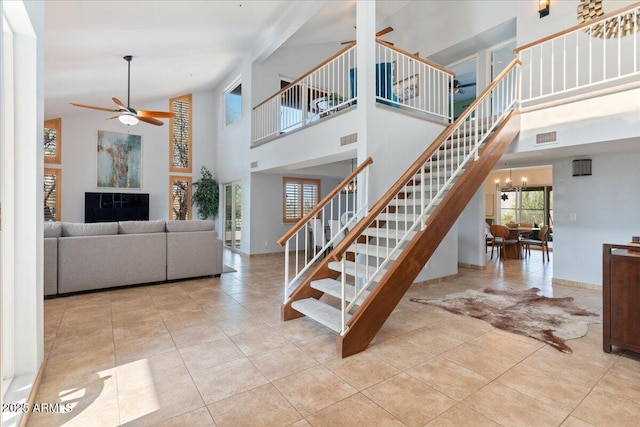 stairs featuring ceiling fan with notable chandelier, a high ceiling, visible vents, and tile patterned floors