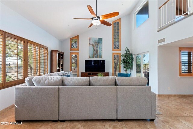 living room with baseboards, a towering ceiling, visible vents, and a ceiling fan