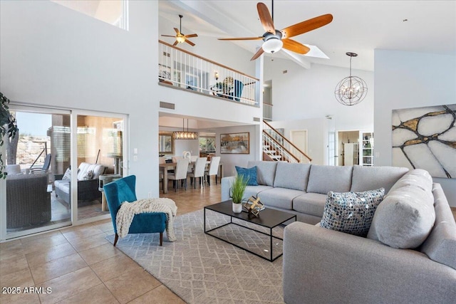 living room featuring stairs, ceiling fan with notable chandelier, light tile patterned flooring, and vaulted ceiling