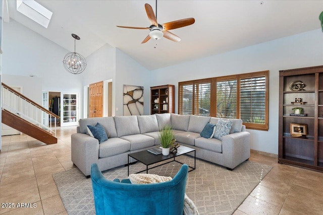 living room featuring a skylight, light tile patterned floors, high vaulted ceiling, and ceiling fan with notable chandelier