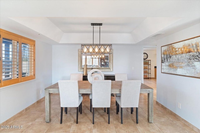 dining space with light tile patterned floors and a raised ceiling