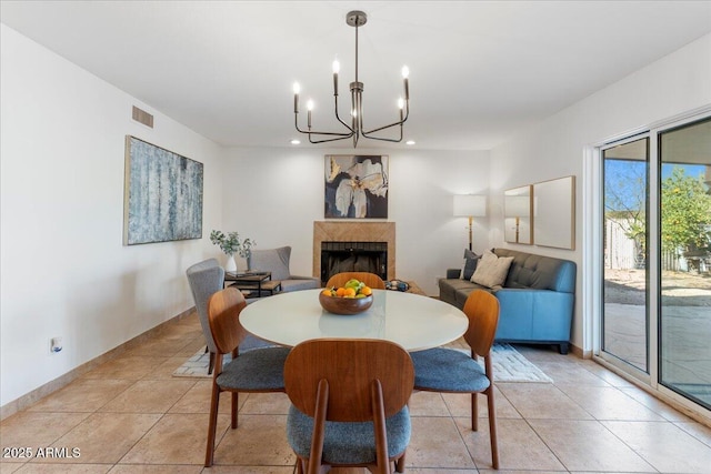 dining room featuring visible vents, a fireplace, a notable chandelier, and light tile patterned floors