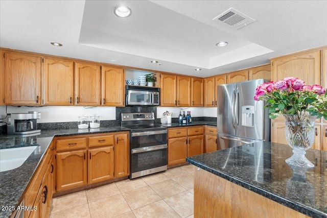 kitchen with visible vents, brown cabinetry, a raised ceiling, stainless steel appliances, and open shelves