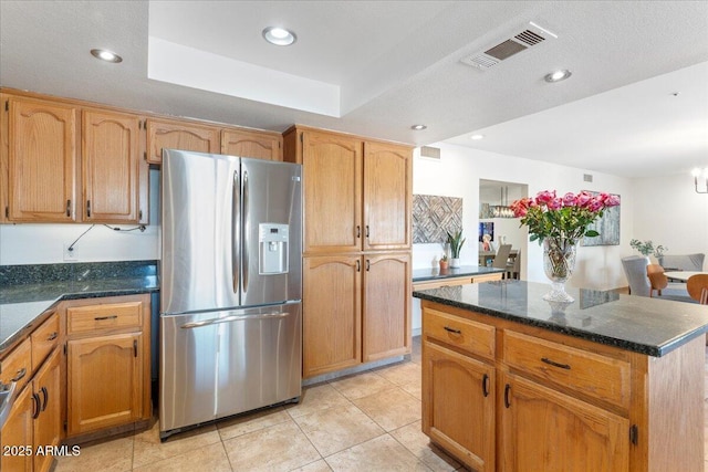 kitchen featuring recessed lighting, visible vents, a center island, a tray ceiling, and stainless steel fridge