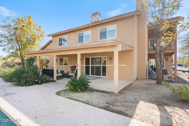 rear view of property with a patio area, a chimney, and stucco siding