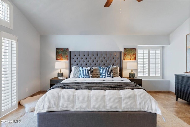 bedroom with lofted ceiling, light tile patterned floors, multiple windows, and a ceiling fan