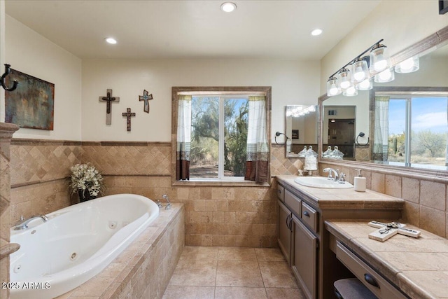 bathroom with a tub with jets, tile patterned floors, vanity, tile walls, and recessed lighting