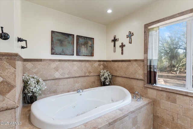 bathroom with a tub with jets, wainscoting, and a wealth of natural light