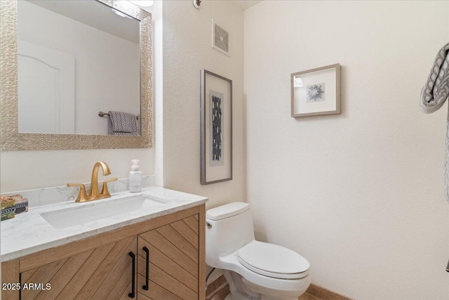 half bathroom with toilet, visible vents, and vanity
