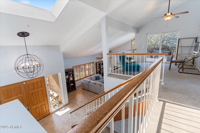 corridor with light carpet, a skylight, a chandelier, an upstairs landing, and high vaulted ceiling