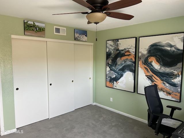 unfurnished office featuring ceiling fan, visible vents, dark carpet, and baseboards