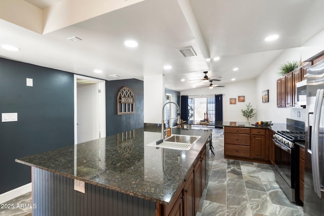 kitchen featuring dark stone counters, stainless steel appliances, a spacious island, and sink