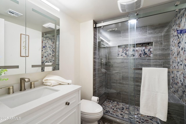 bathroom with toilet, vanity, and a shower with door