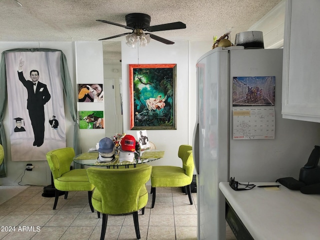 tiled dining area with ceiling fan and a textured ceiling