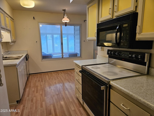 kitchen with light countertops, a sink, light wood-type flooring, black microwave, and range with electric cooktop