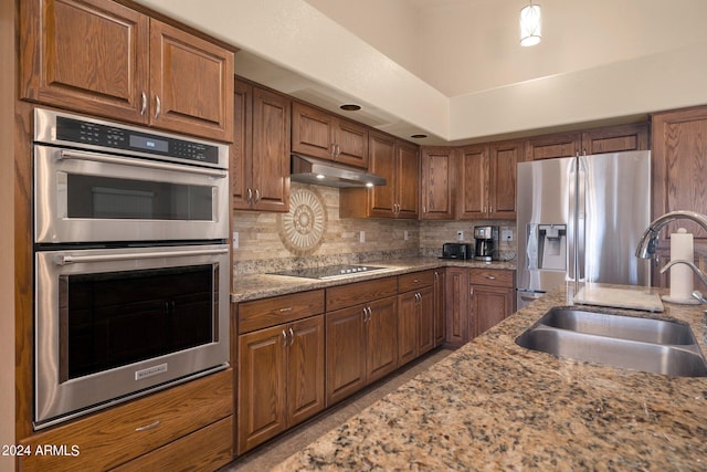 kitchen featuring light stone counters, sink, appliances with stainless steel finishes, and tasteful backsplash