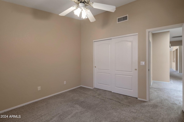 unfurnished bedroom with ceiling fan, light colored carpet, and a closet