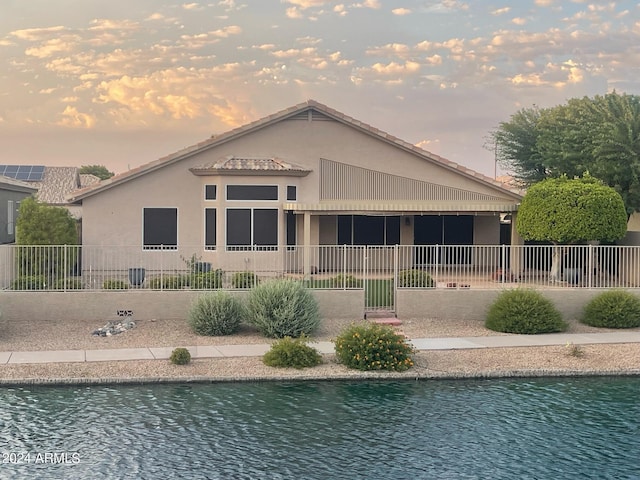 back house at dusk featuring a fenced in pool