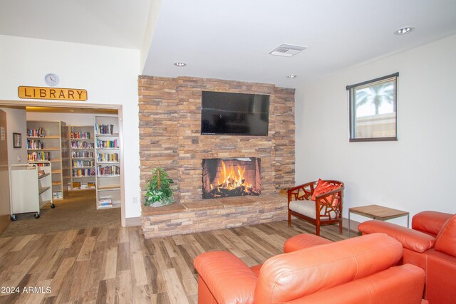 living room featuring a stone fireplace and hardwood / wood-style flooring