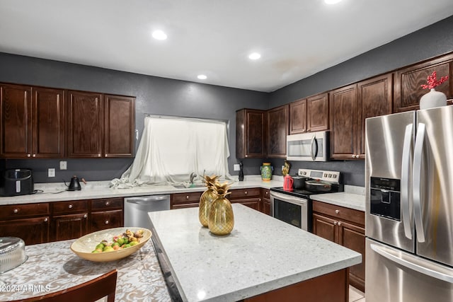 kitchen with appliances with stainless steel finishes, dark brown cabinetry, light stone countertops, and a kitchen island