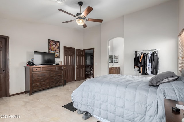 bedroom with light tile patterned flooring, a towering ceiling, ceiling fan, and ensuite bathroom