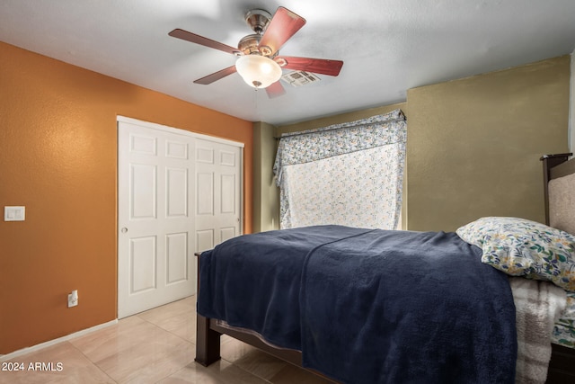 tiled bedroom featuring ceiling fan and a closet