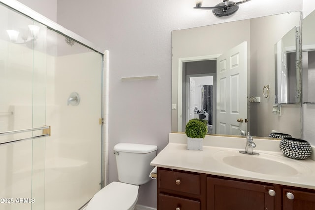 bathroom featuring a shower stall, vanity, and toilet