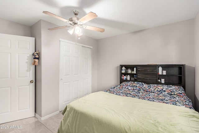 bedroom featuring a closet, light tile patterned flooring, ceiling fan, and baseboards