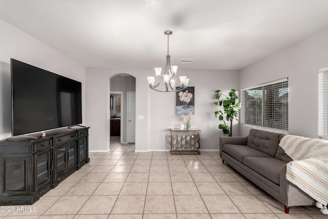 living area featuring arched walkways, light tile patterned floors, visible vents, a chandelier, and baseboards