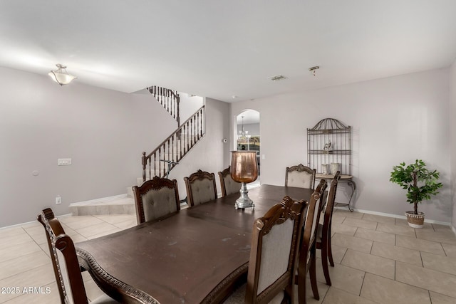 dining space featuring light tile patterned floors, visible vents, stairway, and arched walkways