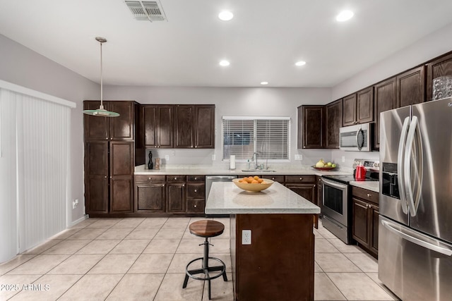 kitchen with a center island, pendant lighting, visible vents, appliances with stainless steel finishes, and a sink