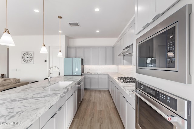 35612 N Lodestone Dr, San Tan Valley, AZ 85144 - kitchen featuring a sink, appliances with stainless steel finishes, light wood-type flooring, decorative backsplash, and pendant lighting
