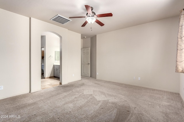 unfurnished bedroom with light carpet, ceiling fan, and ensuite bath