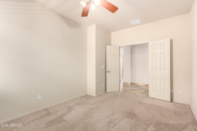 unfurnished bedroom with a closet, light colored carpet, and ceiling fan