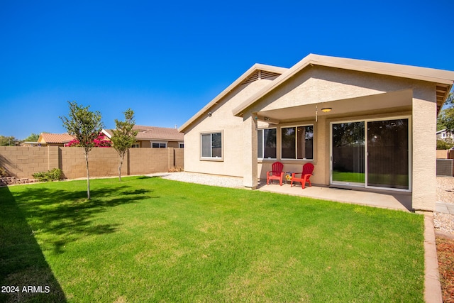 back of property with a patio area and a lawn