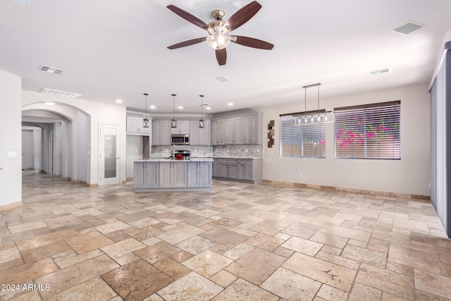 kitchen featuring gray cabinets, a kitchen island with sink, ceiling fan, and pendant lighting