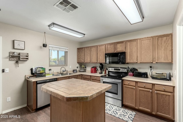 kitchen with sink, a center island, dark hardwood / wood-style floors, and appliances with stainless steel finishes