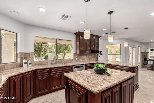 kitchen featuring visible vents, a sink, a peninsula, and a wealth of natural light