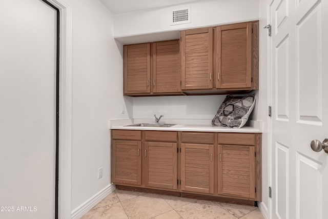 bar featuring a sink, baseboards, light tile patterned floors, and visible vents